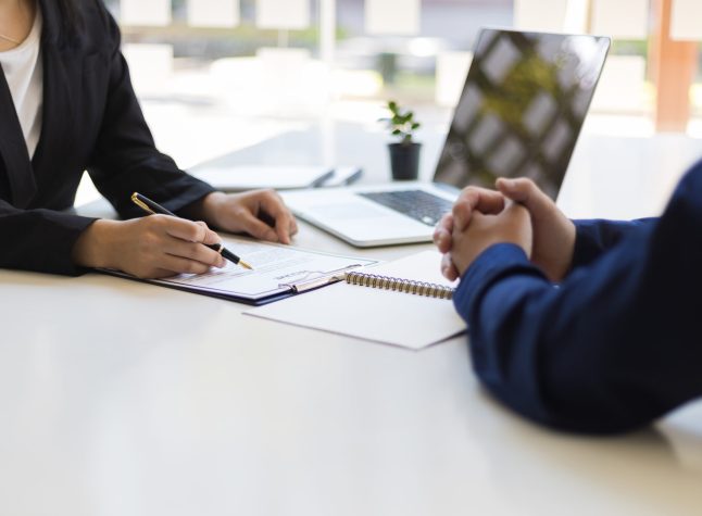 The manager is reading the resume and is interviewing the new employee. Negotiating business and signing a contract. Lawyer and legal advisor.