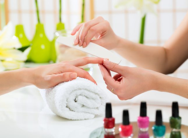 Woman in a nail salon receiving a manicure by a beautician