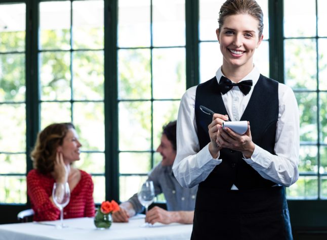 Beautiful waitress writing down an order in restaurant