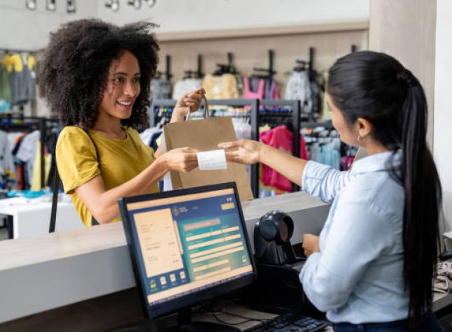 Latin American woman shopping at a clothing store and paying to the cashier - small business concepts